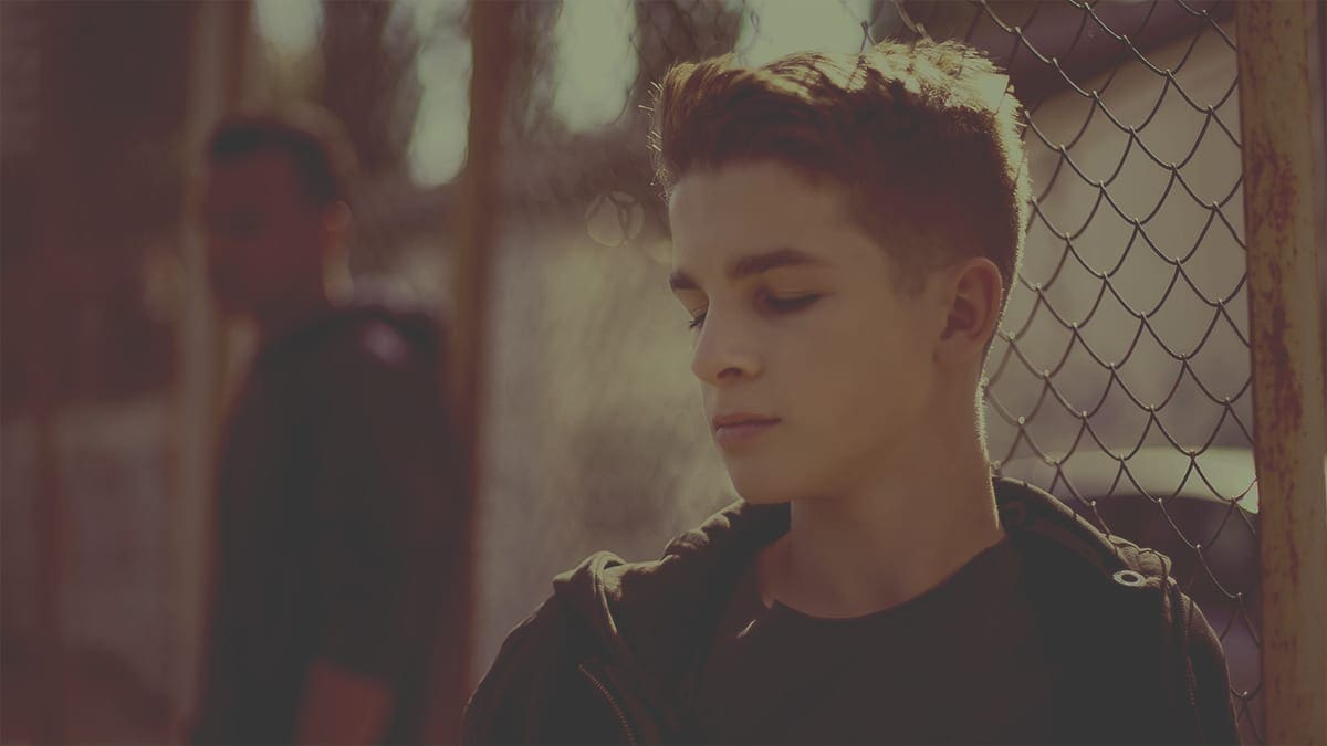 Teenage boys leaning on metal fence, juvenile detention center, orphanage